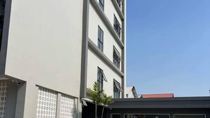 A modern building with a flat facade, large windows, and a covered entrance area. - Hotel Chom Chao City (Phnom Penh)