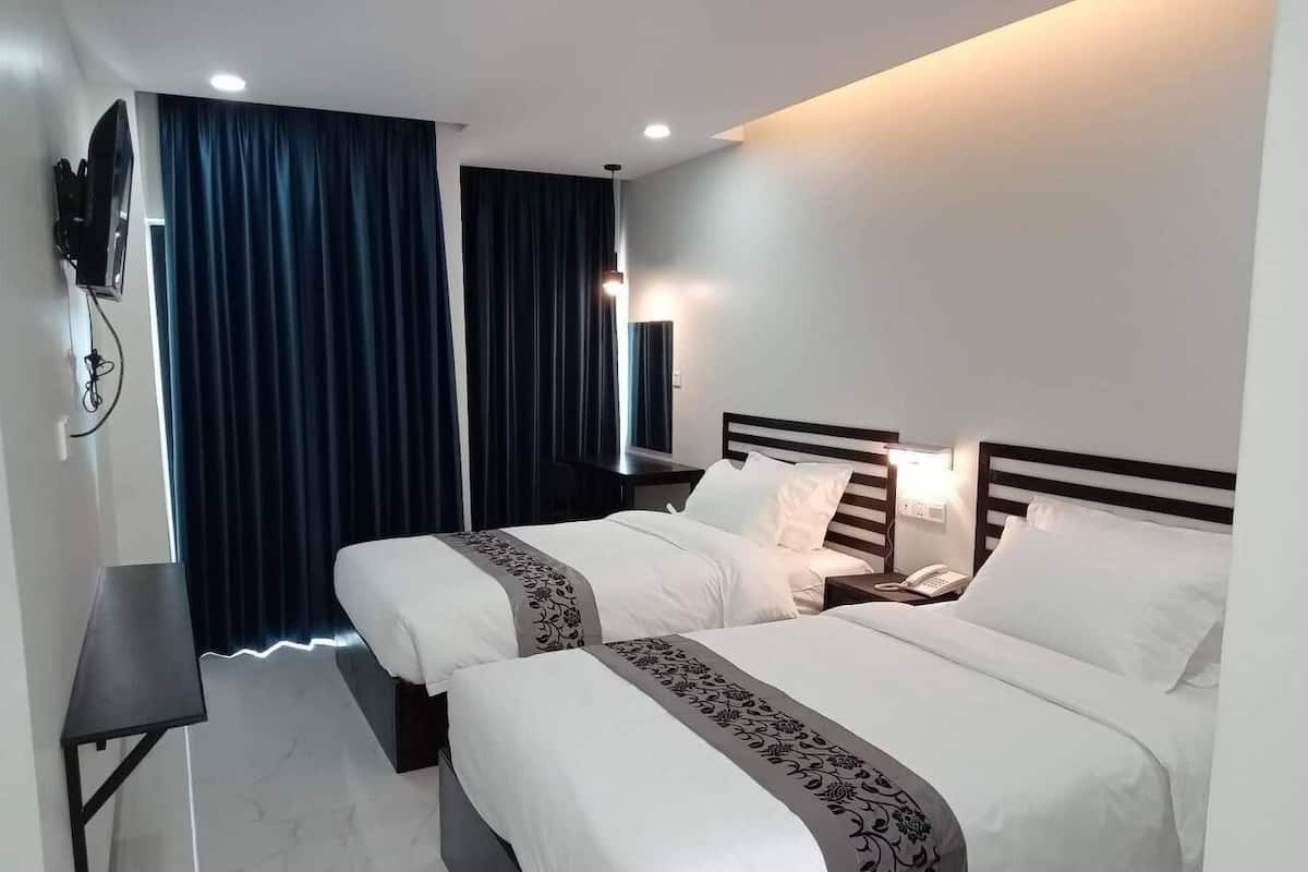 Een hotelkamer met twee bedden, een bureau, een televisie en een telefoon op het nachtkastje.