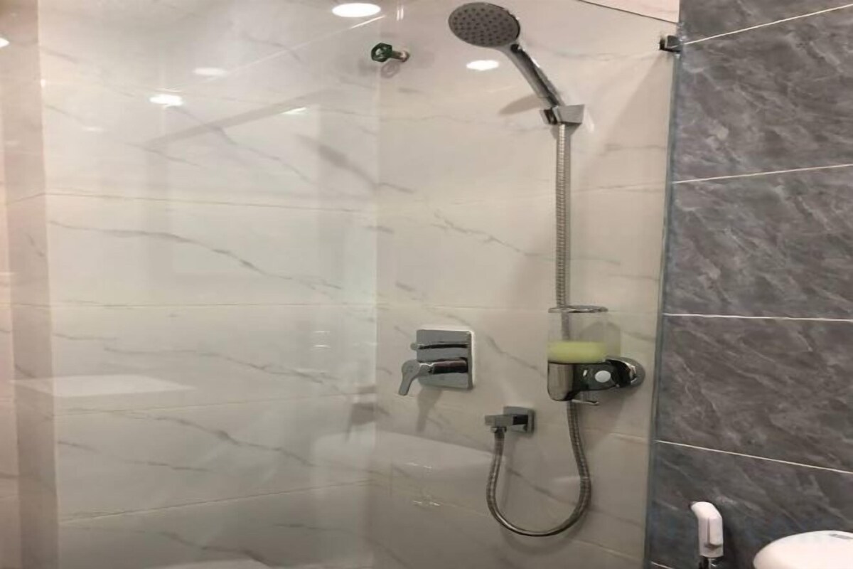 Een douche met een handdouche, een doucheaanslag en een handmatige kraan.