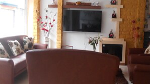 A living room with a flat-screen TV mounted on the wall, a fireplace, and a sofa.