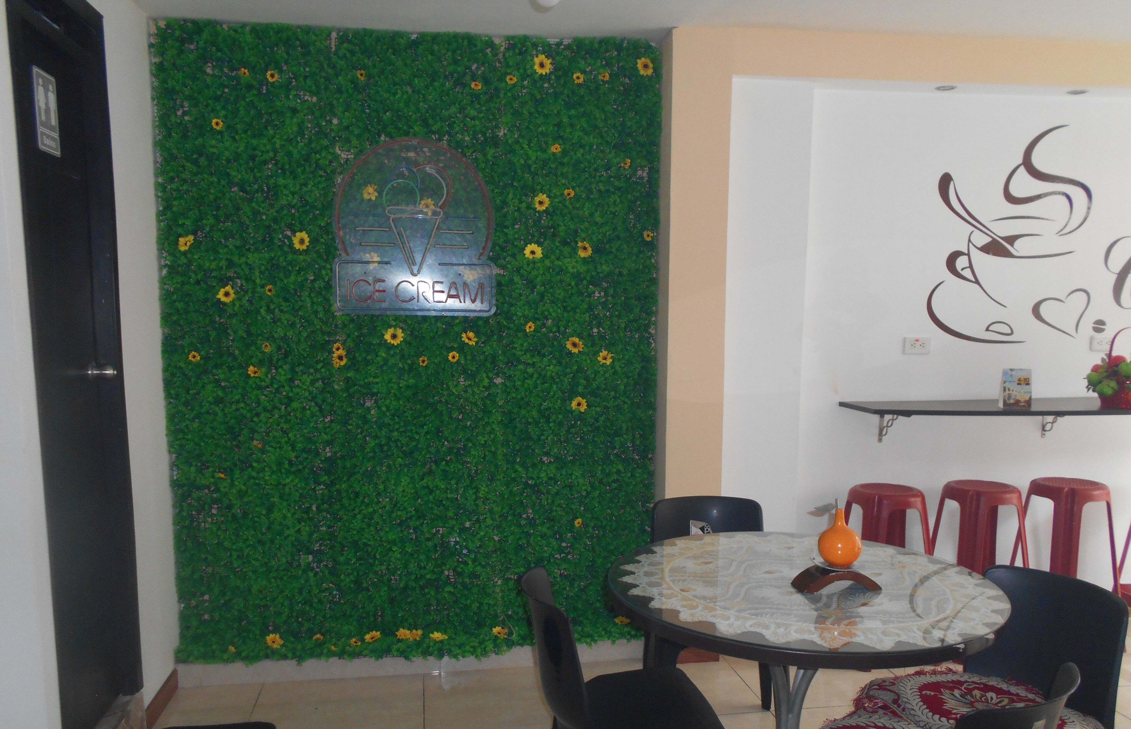 A dining area with a round table, chairs, and a wall decorated with green foliage and sunflowers.