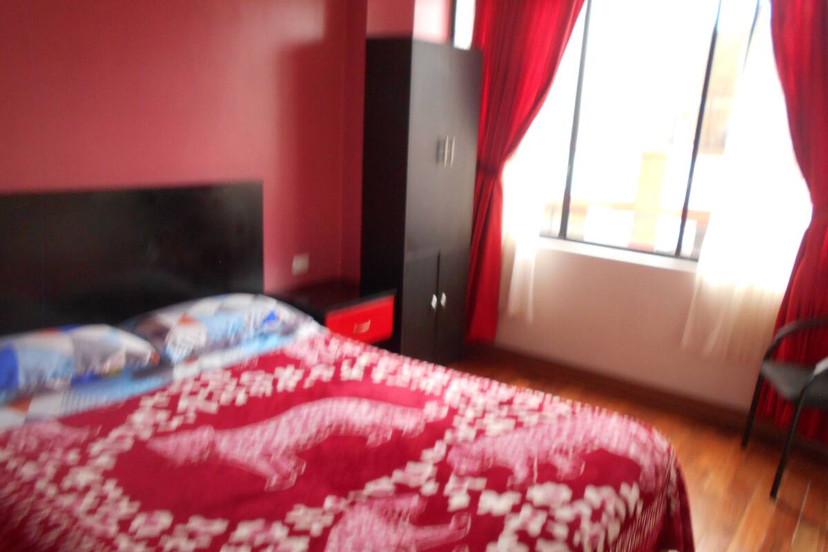 A bedroom with a bed, a wardrobe, and a window with curtains.