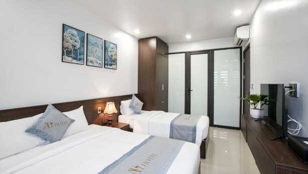 A hotel room with two beds, a TV, a desk, and a wardrobe. - Aui Hotel (Hai Phong)