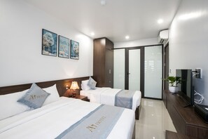 Habitación de hotel con dos camas, televisión, escritorio y armario.