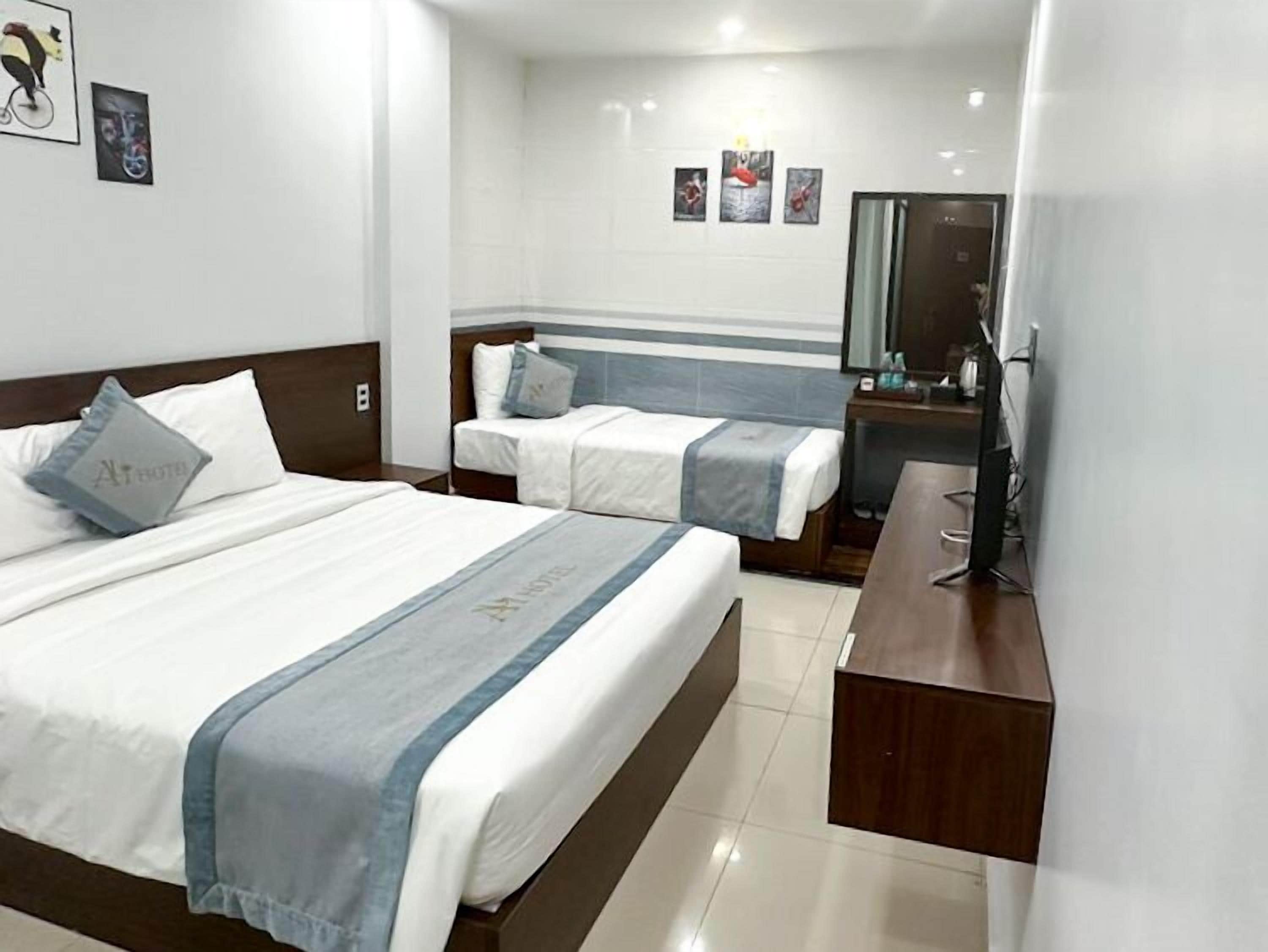 A hotel room with two beds, a wooden headboard, a bedside table, and a mirror.
