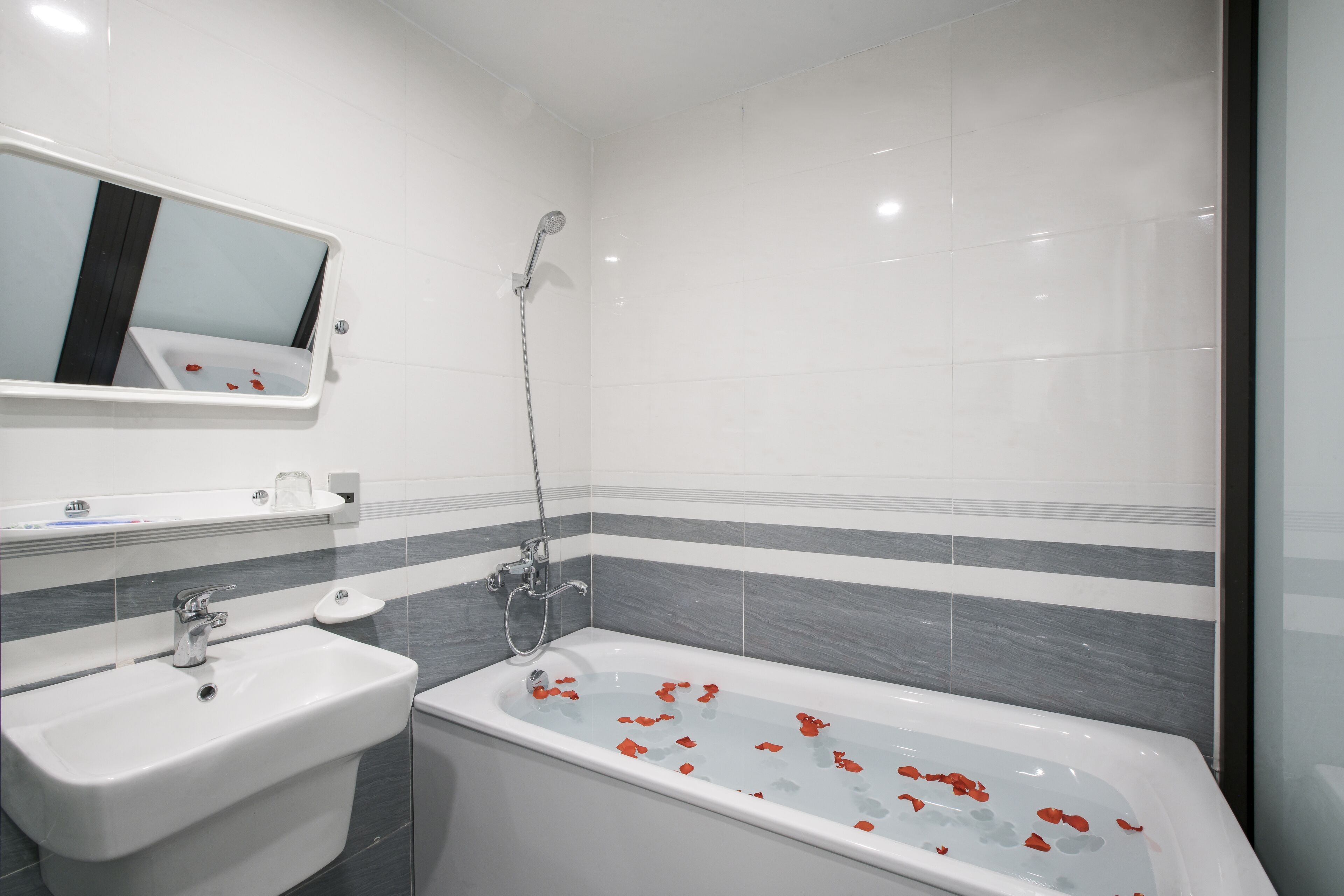 A modern bathroom with a sink, mirror, and bathtub.