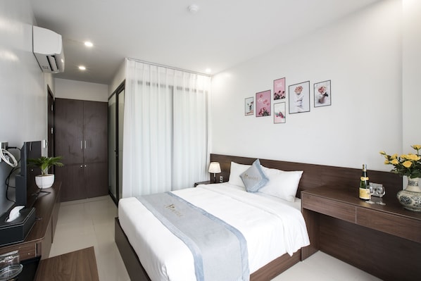Una habitación de hotel moderna con una cama, mesita de noche y un escritorio con ordenador.