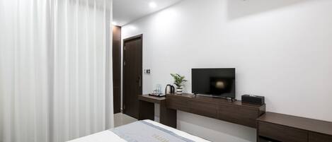 Una habitación de hotel moderna con cama, televisor, escritorio y aire acondicionado.