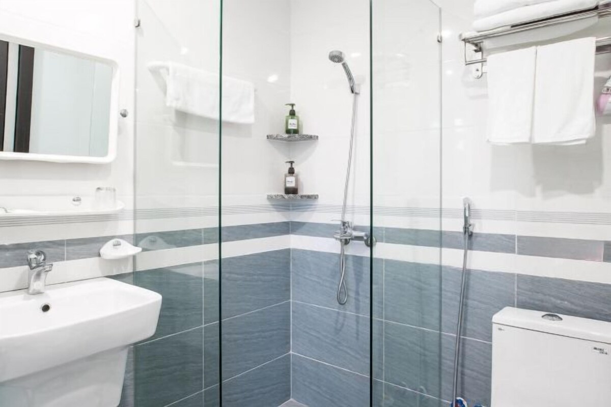 A modern bathroom with a glass shower enclosure, a white sink, and a mirror.