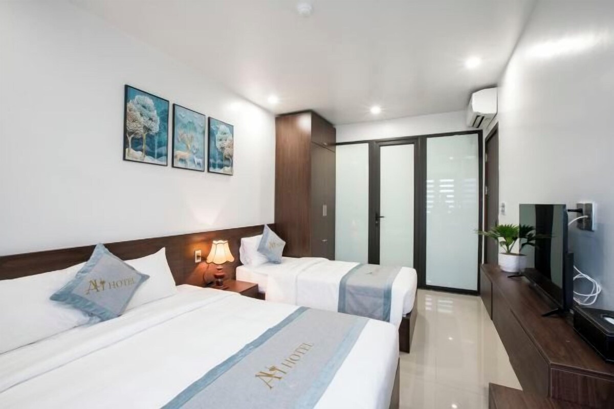 A hotel room with two beds, a TV, a desk, and a sliding door closet.