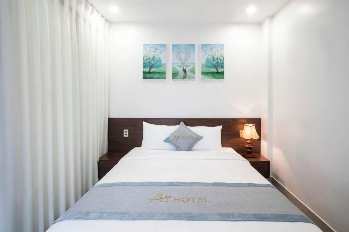Une chambre d’hôtel avec un lit, une table de chevet, une lampe et trois tableaux encadrés accrochés au mur.