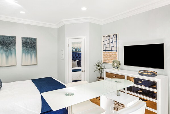 Una habitación de hotel moderna con una cama, una mesa de vidrio, un televisor y obras de arte en las paredes.