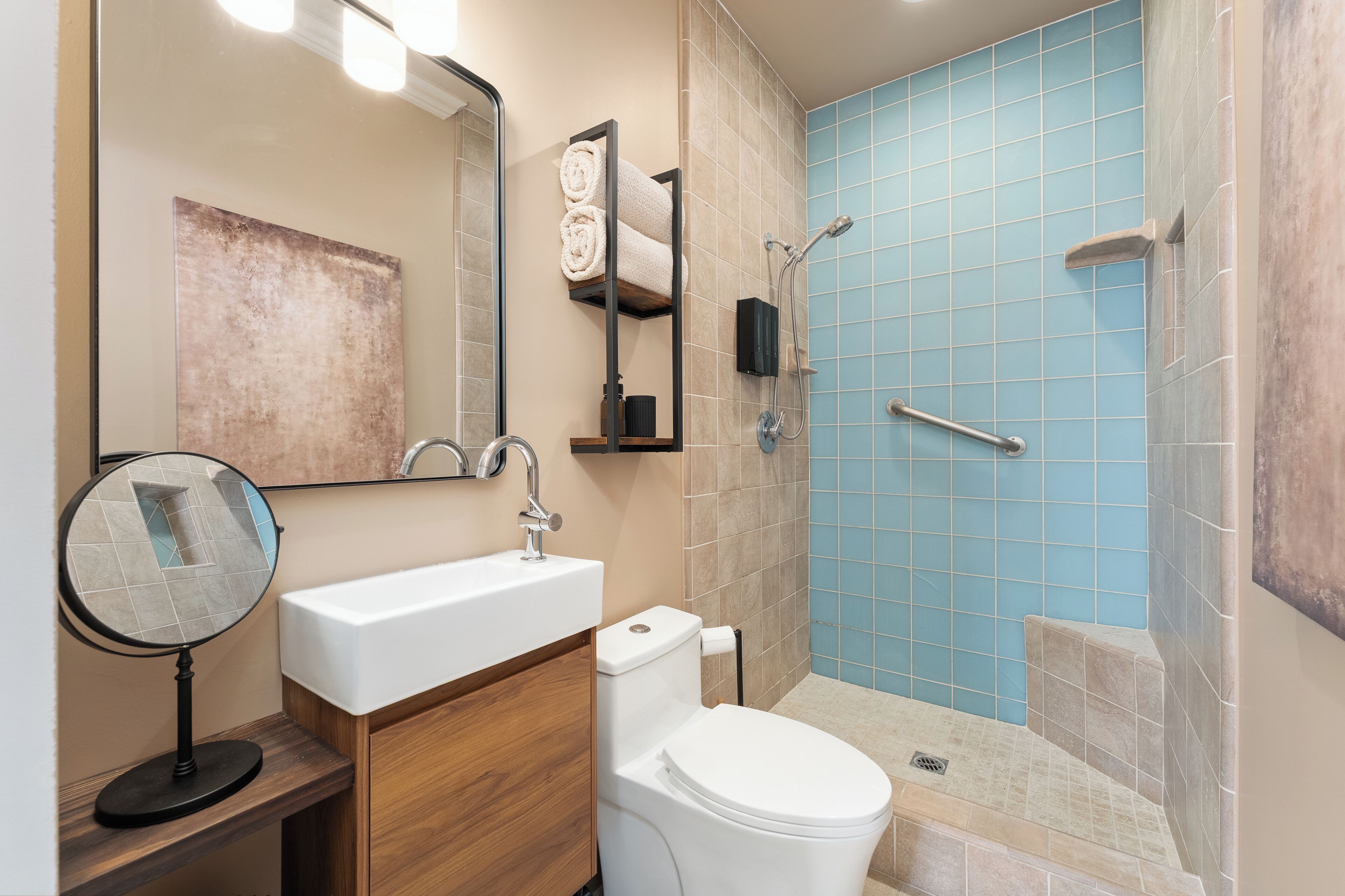 A bathroom with a sink, mirror, toilet, and shower.