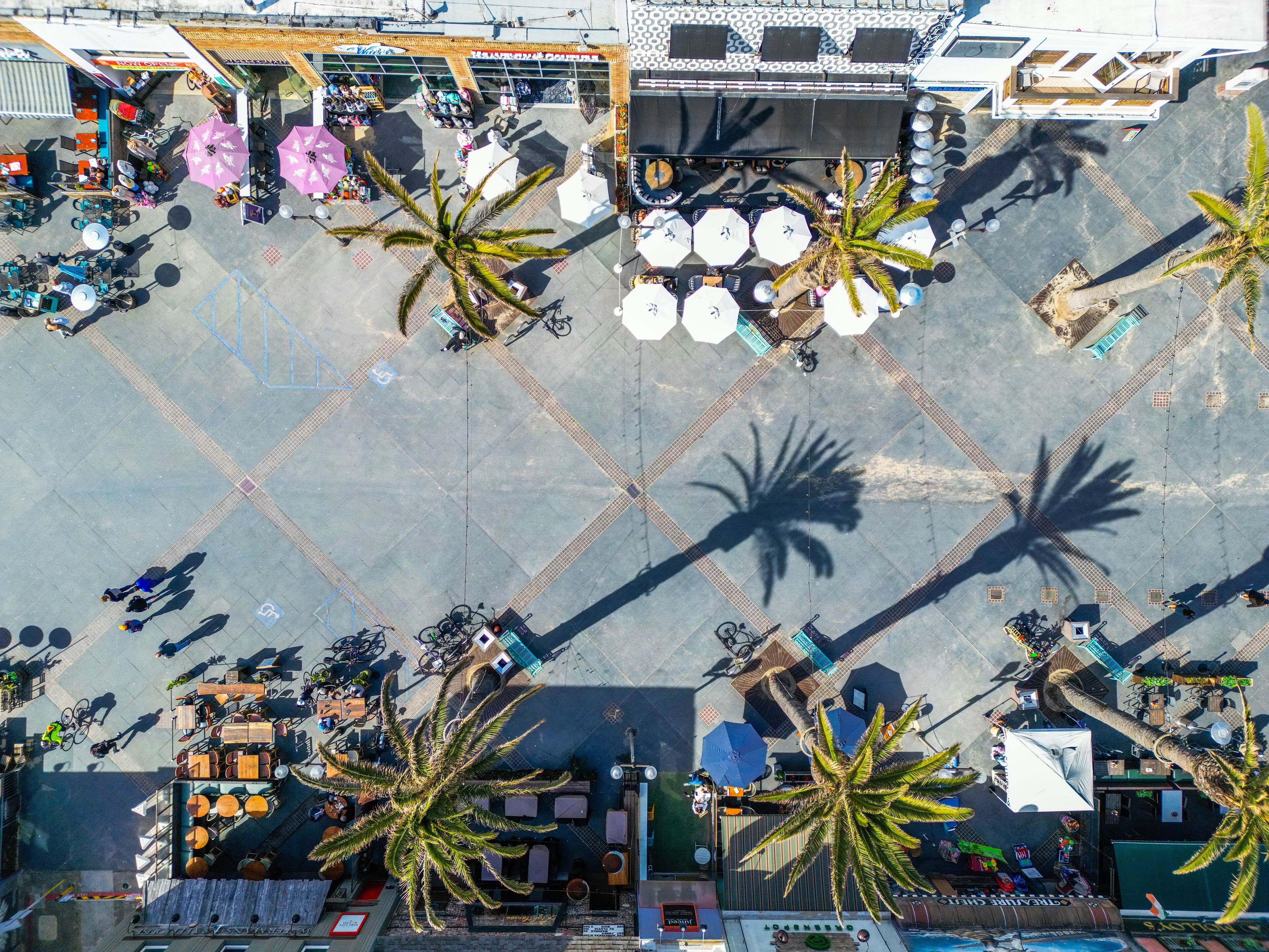 Vista aérea de una plaza pública con zonas de estar, palmeras y un escenario.