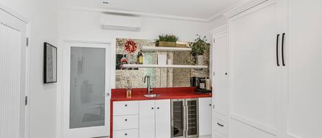 Una cocina moderna con armarios blancos, una encimera roja y un refrigerador para vinos empotrado.