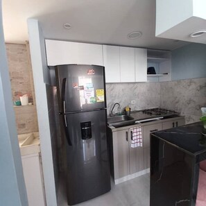 Uma cozinha moderna com geladeira de aço inoxidável, fogão a gás e pia.