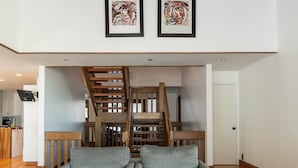 Ein großzügiger Wohnbereich mit hoher Decke, einer Holztreppe und modernen Möbeln.