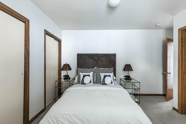 A bedroom with a bed, two bedside tables, a headboard, and a wardrobe.