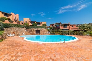 Une piscine avec un mur en pierre et des chaises longues.