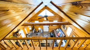 A wooden cabin with a sloped roof, a dining area, and a kitchen.