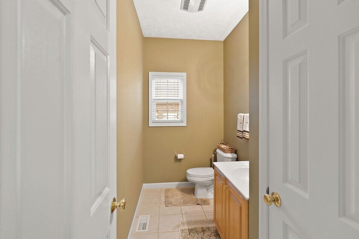 A bathroom with a toilet, sink, and window.