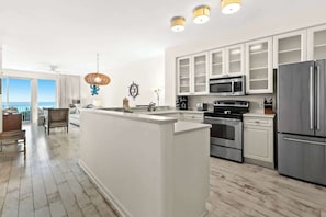 A modern kitchen with white cabinetry, stainless steel appliances, and a large island. - The Crescent 309 (Miramar Beach)