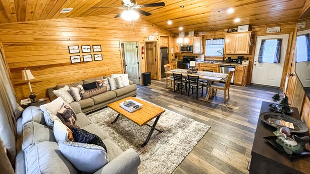 A spacious living area with a wooden ceiling, a dining table with chairs, and a kitchen in the background. - Cabin #3 • 1 Mile to DeGray Lake (Bismarck)