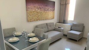 Una sala de estar moderna con una mesa de comedor preparada para cuatro personas, un sofá gris y un sillón gris.