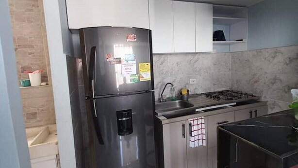 Una cocina moderna con un refrigerador de acero inoxidable, una estufa a gas y armarios blancos.