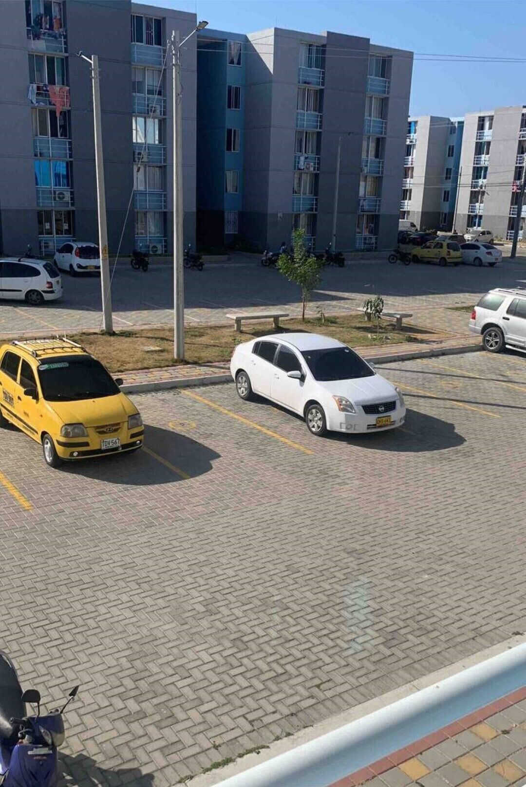 A parking lot with a white car and a yellow taxi.