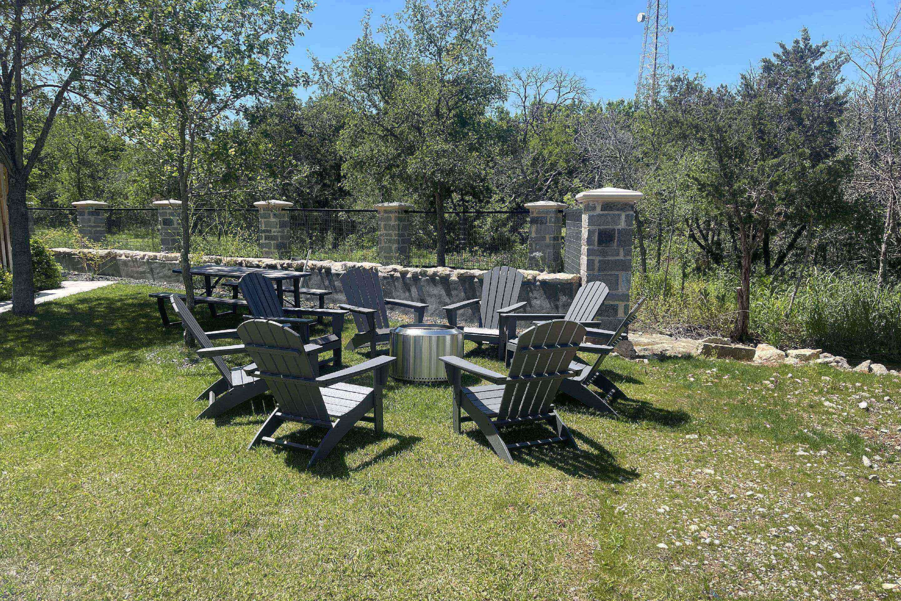 An outdoor patio area with Adirondack chairs and a stone fire pit.