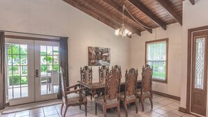 A dining area with a wooden table and chairs, a chandelier, and a painting on the wall.