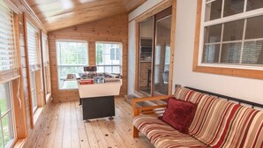 A cozy room with a wooden floor, a sofa with a striped cushion, and a foosball table.