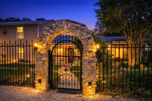 A gated entrance with a stone archway, a metal gate, and a building with a star emblem. - Secluded Lakehouse w/ Private Cove Access | Foosball & Basketball Court | Family Retreat (Laguna Park)