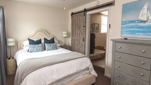 A bedroom with a bed, bedside lamps, a dresser, and a painting of a sailboat. - Casa del Lago! Lakefront Retreat with Semi-Private Cove, Deck, and Firepit - Ideal for R&R! (Laguna Park)