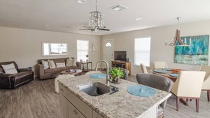 A spacious living area with a kitchen island, dining table, and seating.