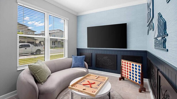 A living room with a sofa, a coffee table, a flat-screen TV, and a dartboard. - Hi110sd: 6 Bed, Enchanted House, Gameroom (Melbourne Beach)