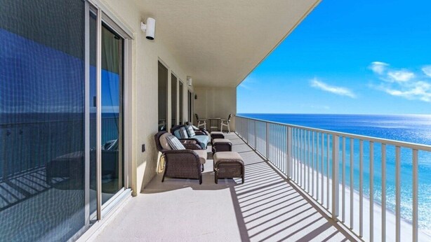 A balcony with a view of the ocean, furnished with a sofa and chairs, and a railing. - Gulfcrest 19th-Floor | Beachfront | Huge Balcony (Panama City Beach)