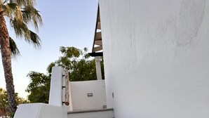 A staircase with white walls and a wooden handrail, leading to a covered area with a palm tree in the background. - At the best location and ocean view (Loreto)