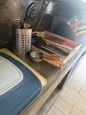 A kitchen counter with various utensils, a colander, a whisk, and a metal container.