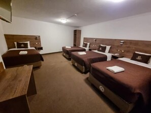 A hotel room with four beds arranged in a row, a wooden headboard, a flat-screen TV mounted on the wall, and a small table. - Hotel San Francisco Pardo Cusco (Cusco)