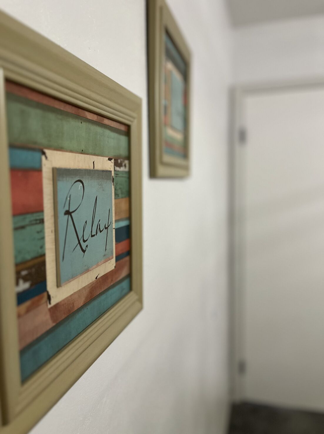 A hallway with a framed sign that reads "Relay" on the wall.