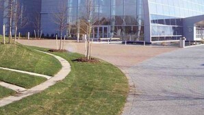 A modern glass building with a unique angular design, surrounded by a well-maintained lawn and a paved walkway. - Cute 4 bed 2.5 bath Home - Sleeps 12! 30 night min (Virginia Beach)