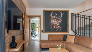 A modern living room with a brown sofa, a wooden coffee table, and a large floral artwork on the wall.