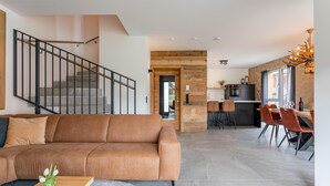 A modern living room with a brown sofa, a wooden coffee table, and a staircase.