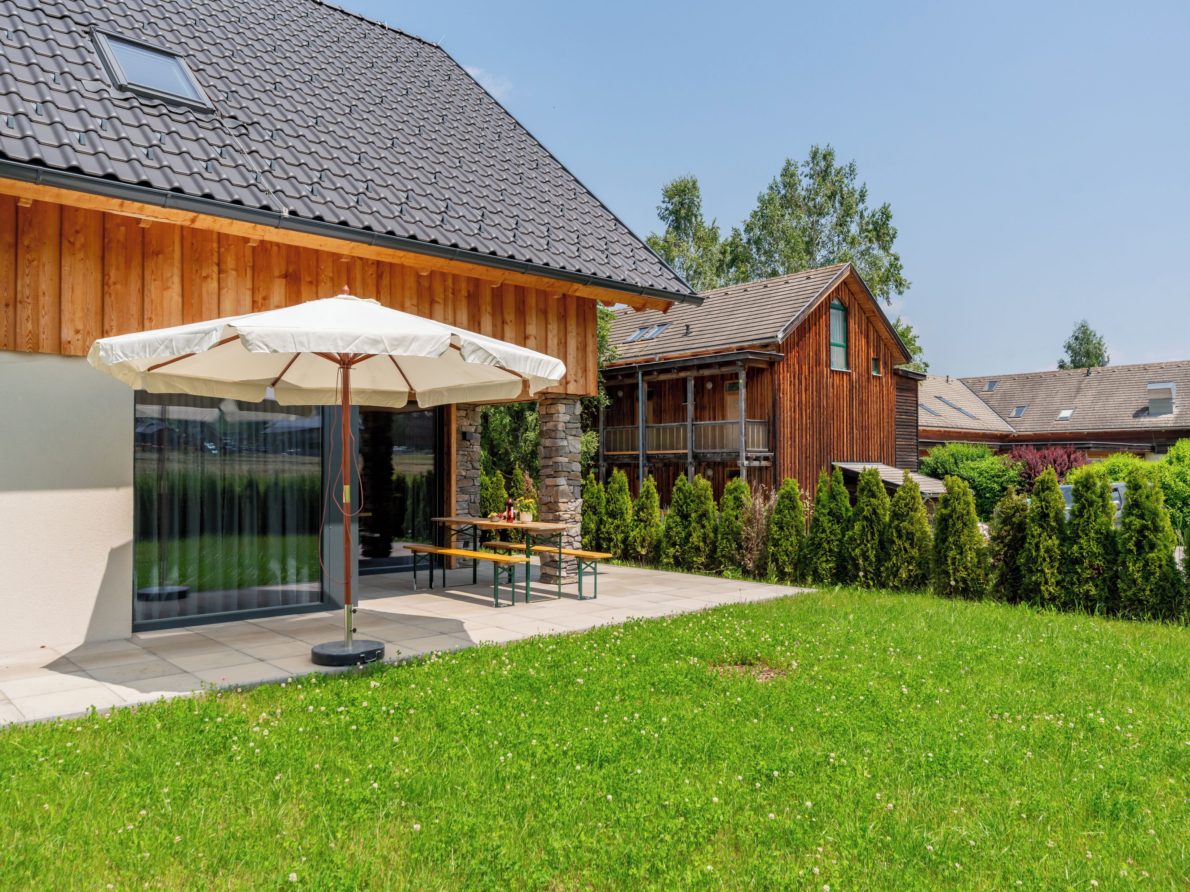 Una casa de madera con un patio, una mesa y una sombrilla.