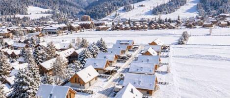 Un pueblo cubierto de nieve con casas de madera y una montaña al fondo.