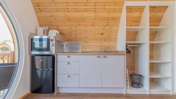 Une cuisine compacte équipée d’un four à micro-ondes, d’un réfrigérateur et de meubles de rangement blancs.
