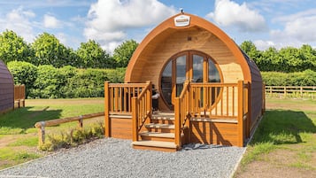 Une structure en bois en forme de dôme, dotée d’une porte circulaire et d’une enseigne au-dessus.
