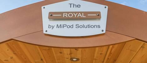 A sign with the text 'The ROYAL by MiPod Solutions' mounted on a structure with a wooden interior.